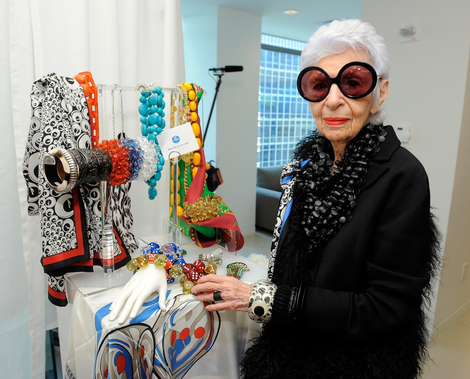 התמונה עשויה להכיל Iris Apfel אביזרים משקפיים אדם מבוגר אנשים טבעת תכשיטים מכשיר חשמלי ומיקרופון