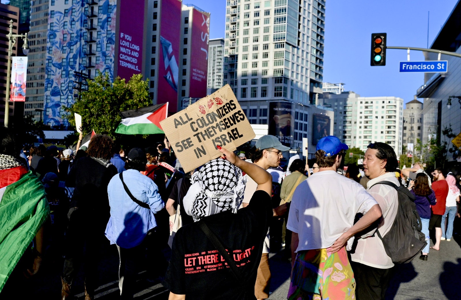 התמונה עשויה להכיל אור עיר רמזור תיק תיק בגדים כובע מצעד אדם מחאה עירוני מבוגר ודגל