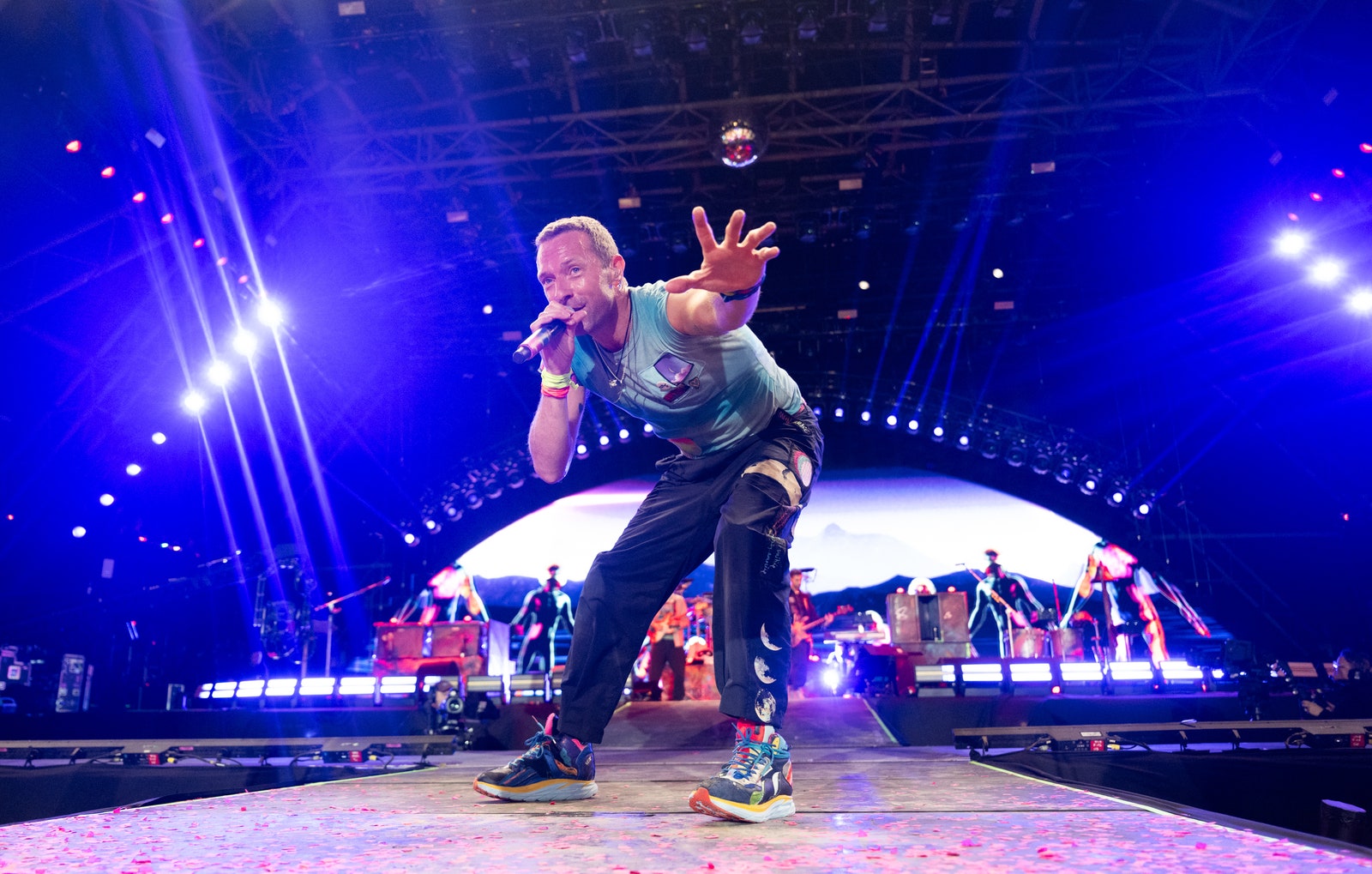 התמונה עשויה להכיל את Chris Martin Lighting Performer Person Performance Solo ביגוד למבוגרים הנעלה נעליים וקונצרטים