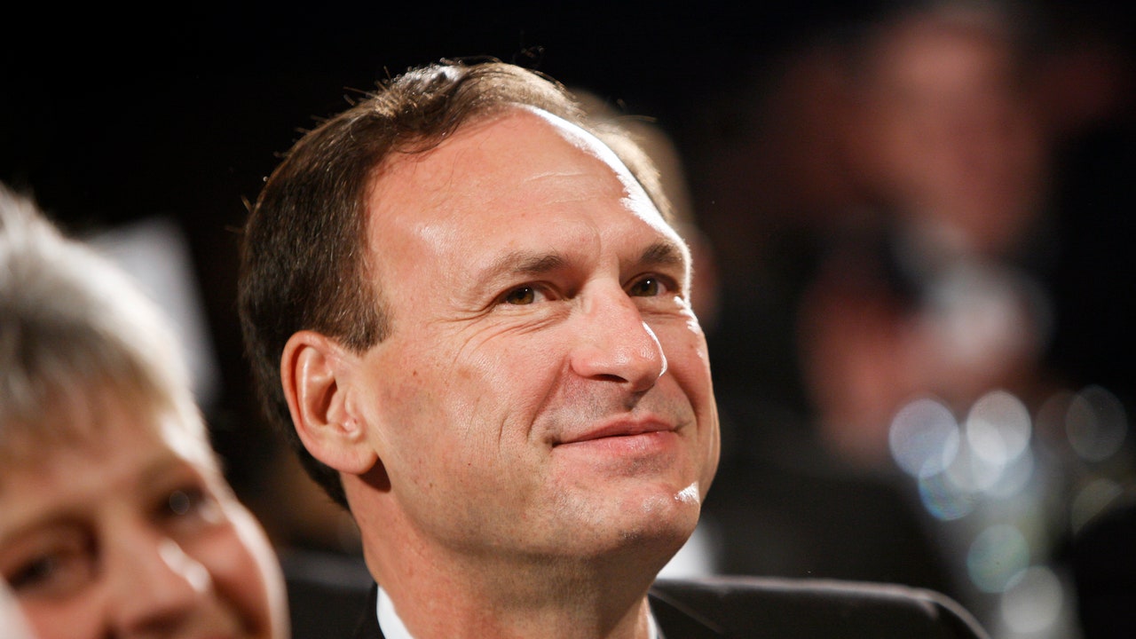 אשתו של סמואל אליטו מפנטזת בגלוי על הנפת דגל אנטי-גאווה עם המילה האיטלקית ל"בושה" מוקפת בלהבות