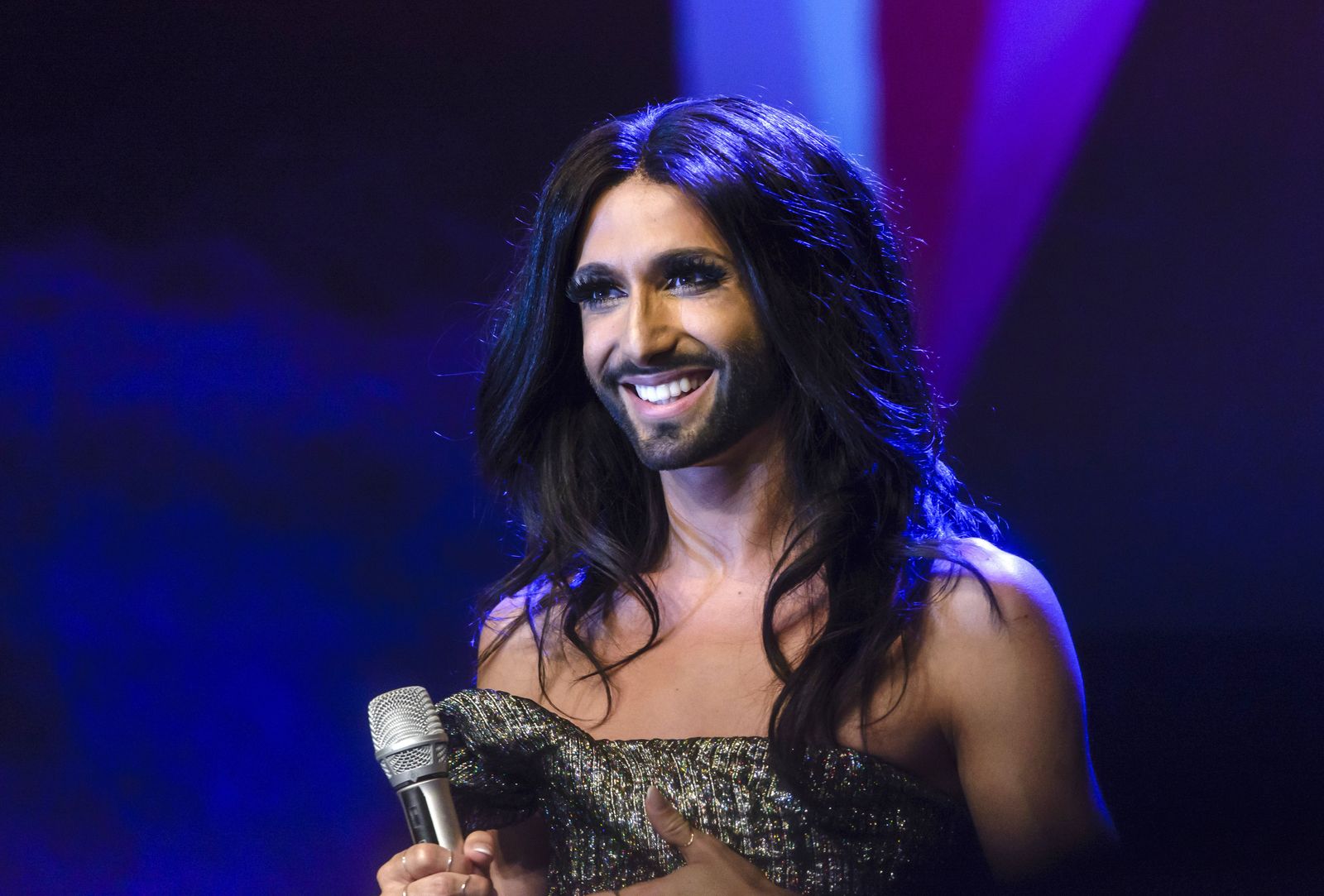 תמונה עשויה להכיל Conchita Wurst מכשיר חשמלי מיקרופון פרפורמרית אדם ביצוע סולו ראש ופנים למבוגרים