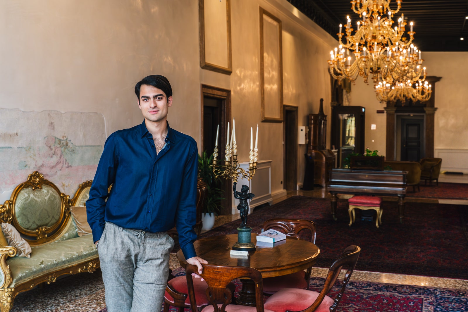 תמונה עשויה להכיל אדוארדו בריטו נברשת מנורה לאדם מבוגר ריהוט ריהוט צמח מקלדת ומכשיר נגינה