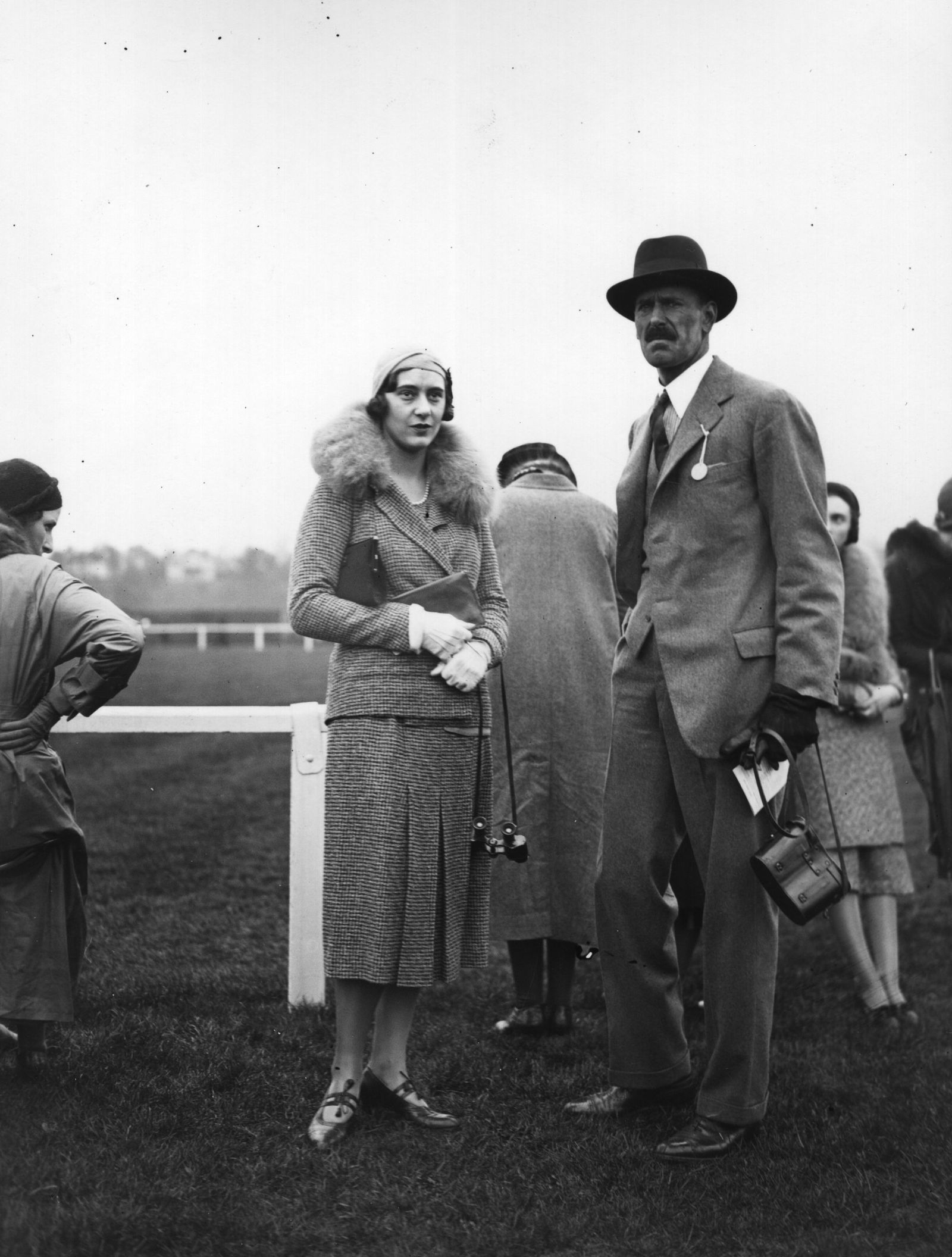 התמונה עשויה להכיל בגדים מעיל אדם אביזרי תיק תיק יד למבוגרים חליפת לבוש רשמי כובע כפפה דשא וצמח