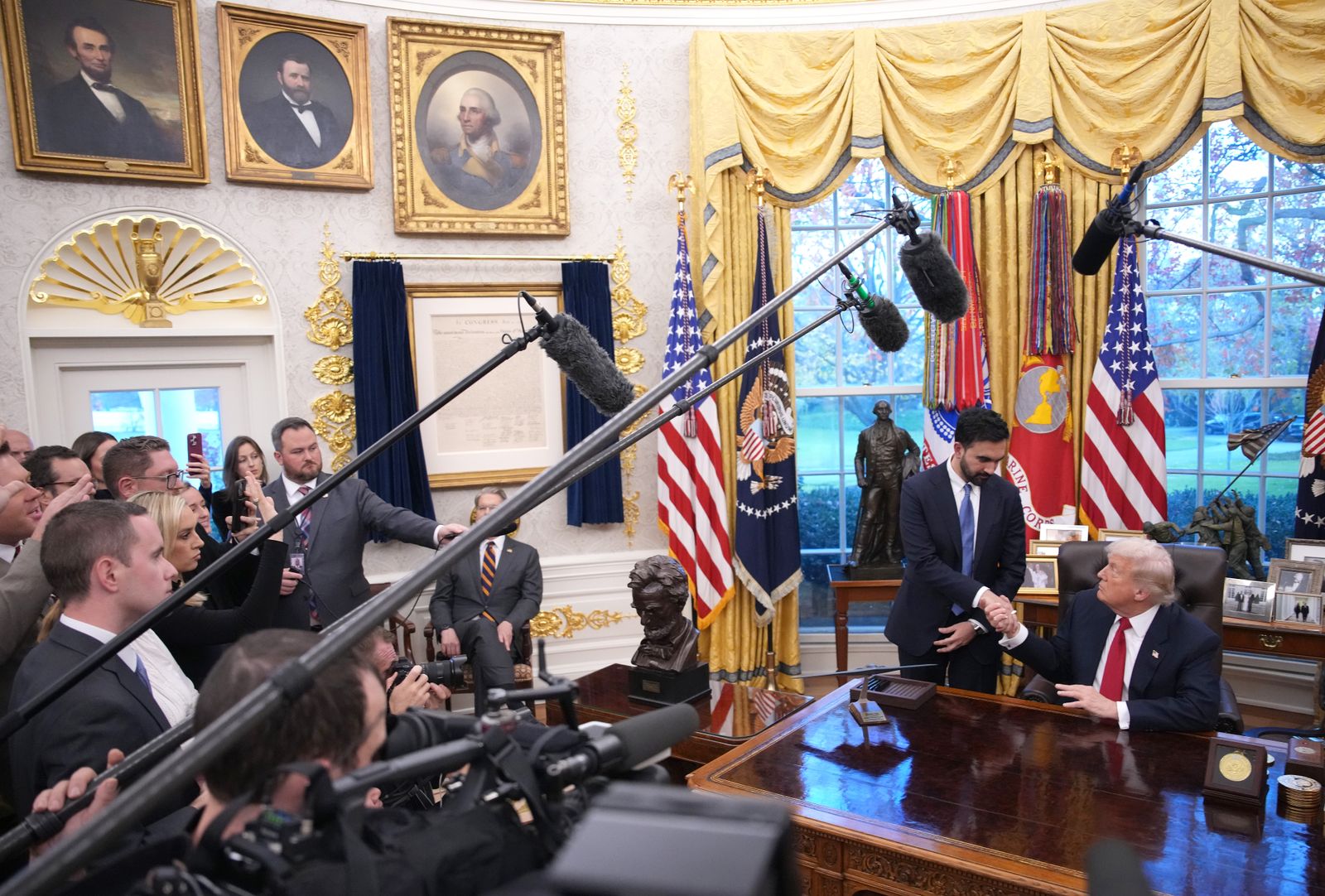 התמונה עשויה להכיל אדם מבוגר אביזרי מיקרופון מכשיר חשמלי ללבוש פורמלי עניבה בתוך קהל ופנים