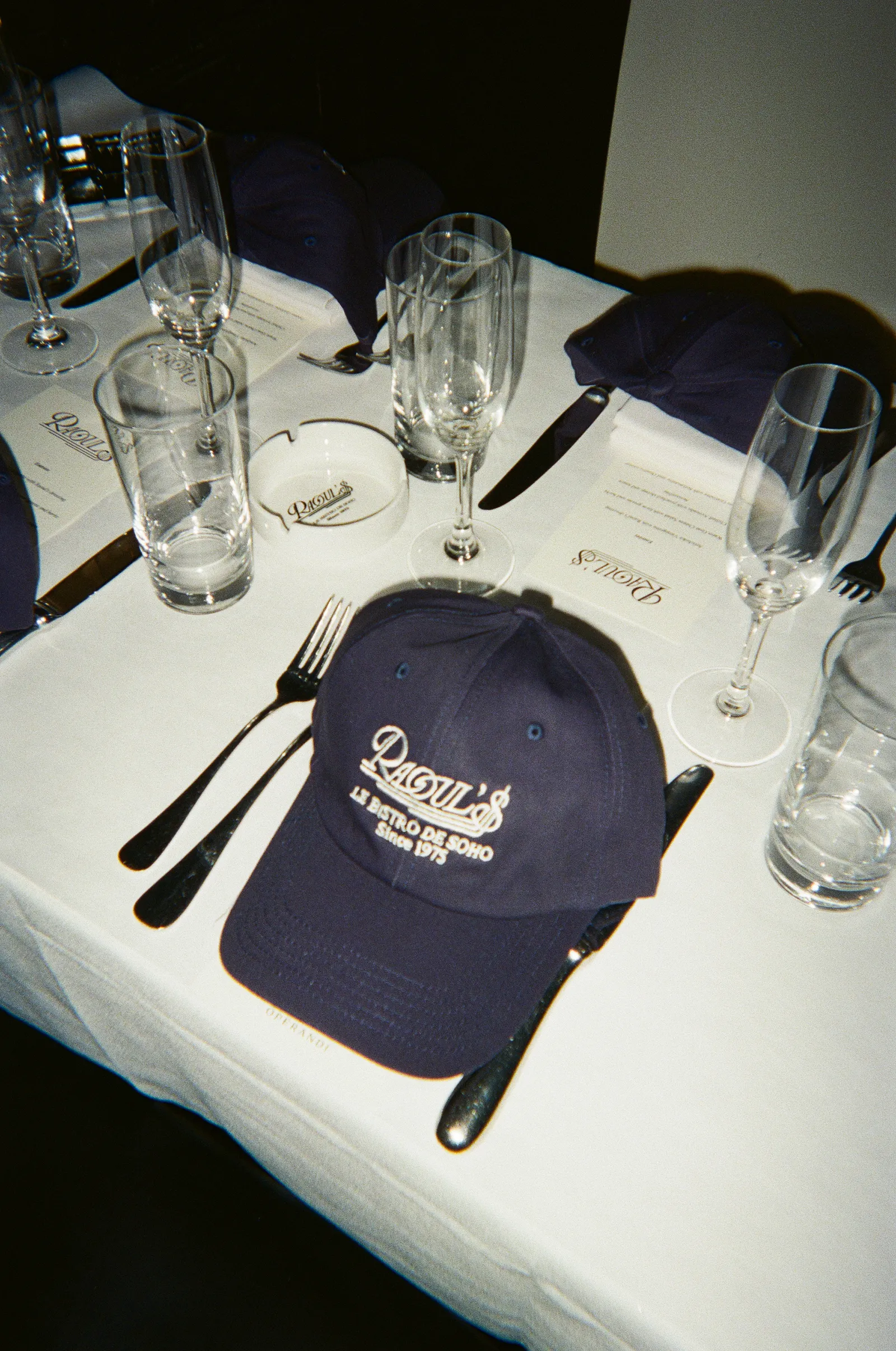 התמונה עשויה להכיל כובע בייסבול כובע כובע שולחן אוכל ריהוט שולחן סכו