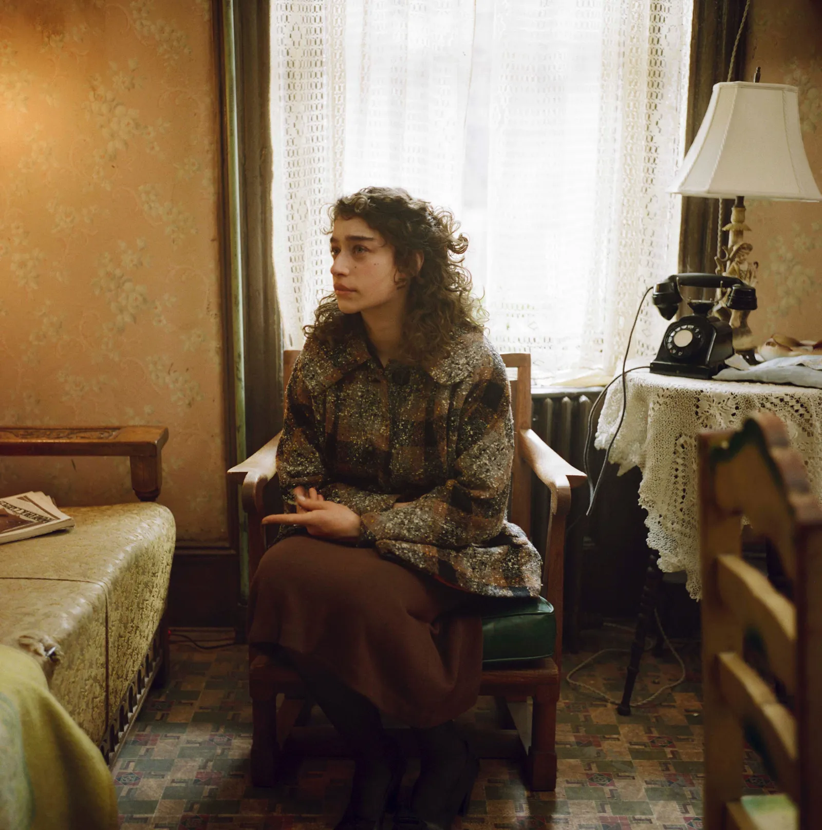 התמונה עשויה להכיל אדם מבוגר כיסא ריהוט יושב שיער שיער מתולתל ביגוד הנעלה נעלי עקב ופנים