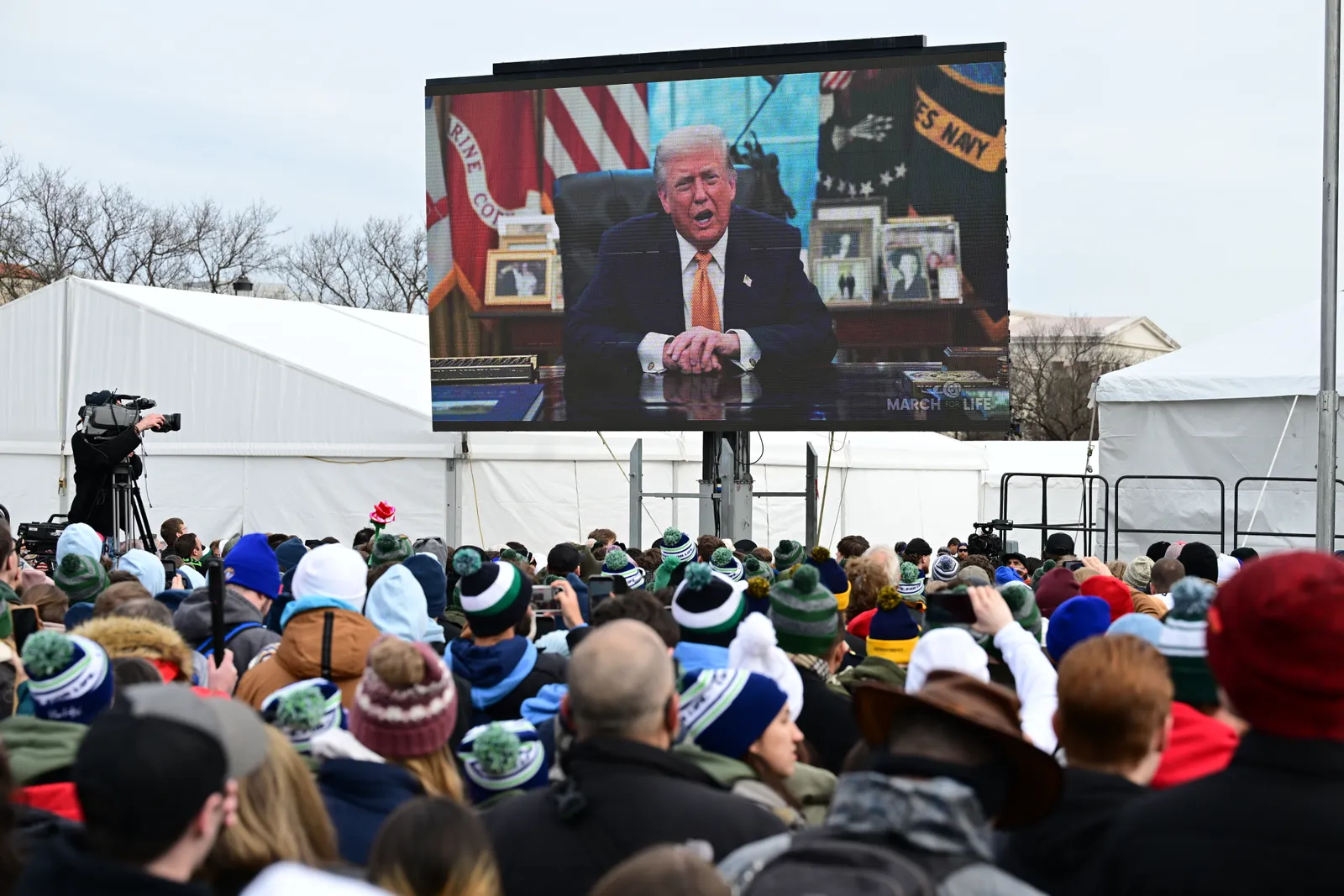 התמונה עשויה להכיל את דונלד טראמפ אנשים אדם קהל אנשים אלקטרוניקה למבוגרים ביגוד מסך כובע פנים ראש וכובע