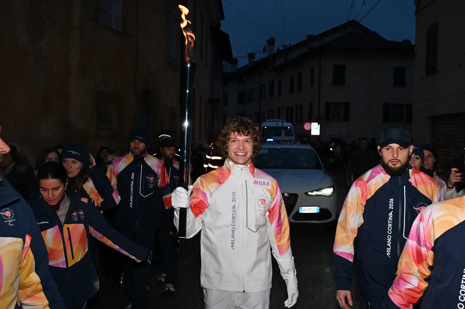 התמונה עשויה להכיל את Micah Fowler Bryn Christopher Light Person Adult Torch Urban Clothing מעיל ורכב