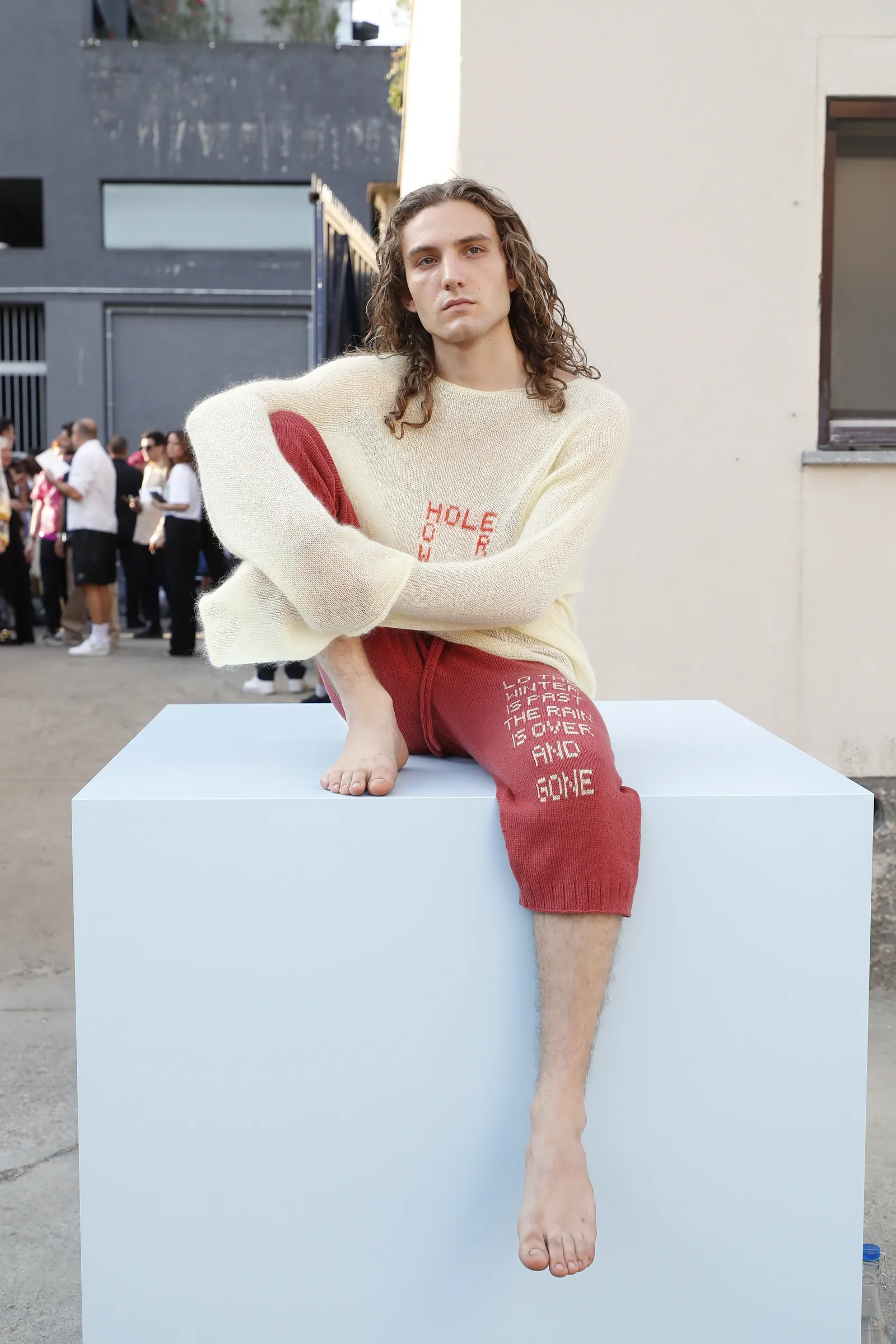 התמונה עשויה להכיל Eugenio Siller Person יושב בגדים למבוגרים מכנסיים סריגים וסוודר