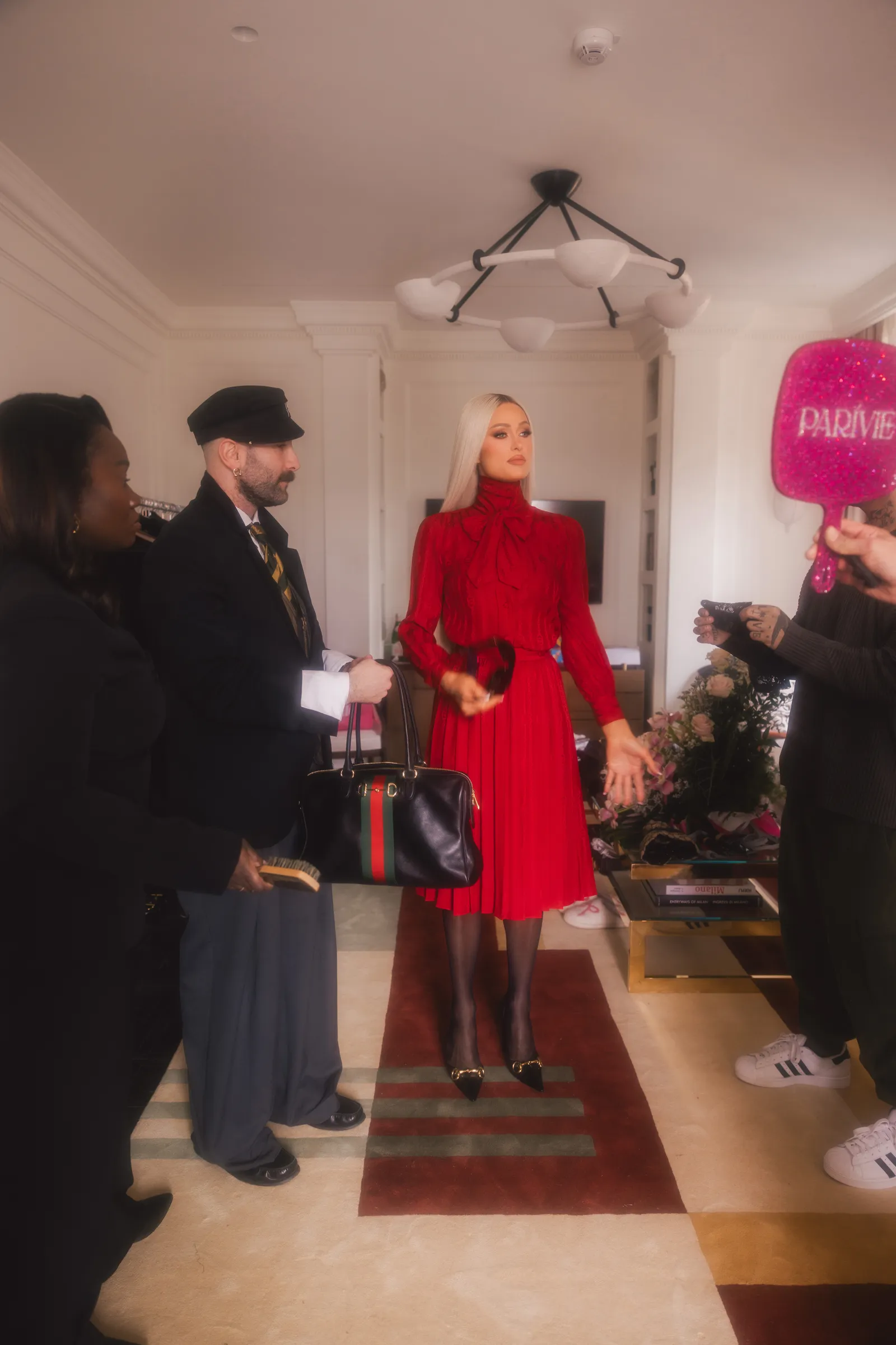 התמונה עשויה להכיל פריס הילטון תאורה בגדי אדם מבוגר אביזרי חליפה ללבוש רשמי תיק ותיק