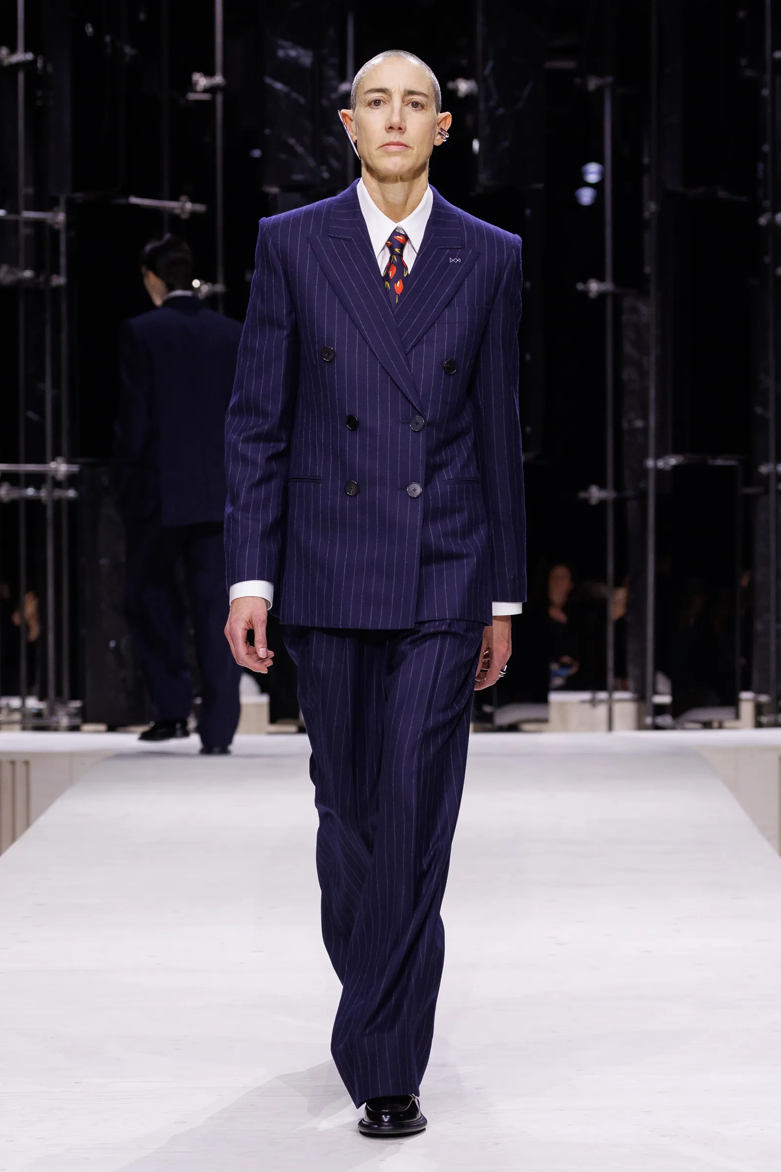 התמונה עשויה להכיל בגדים לבוש רשמי חליפת אדם מבוגר מעיל ועמידה