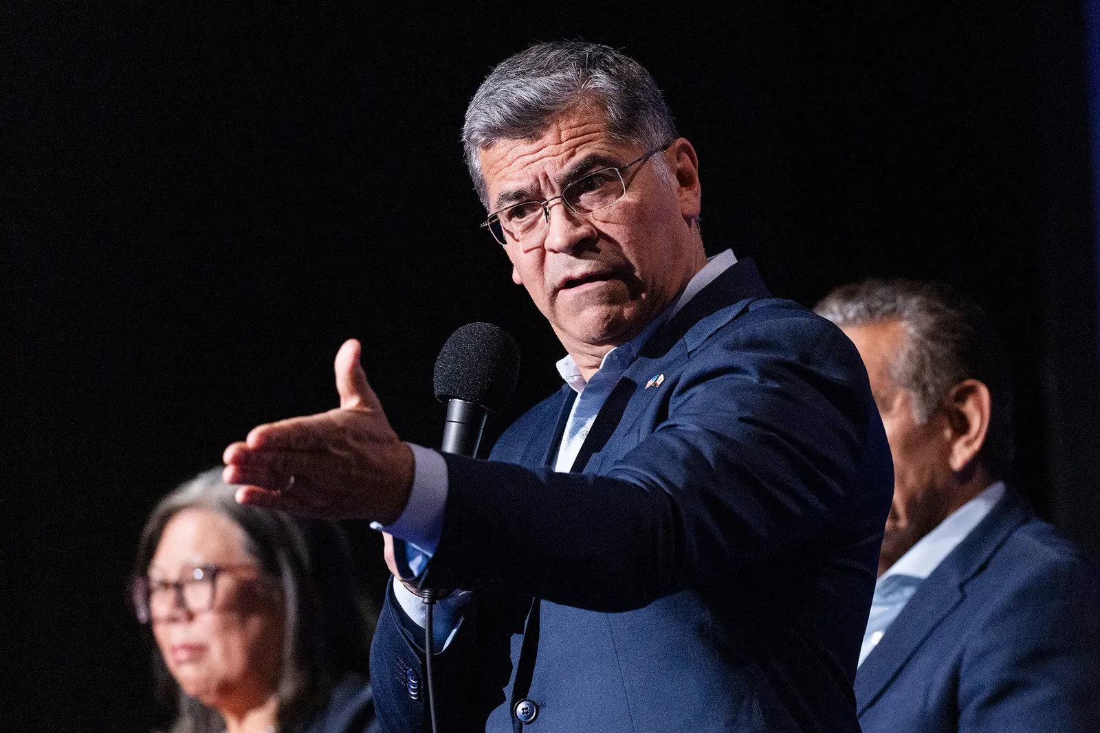 התמונה עשויה להכיל את Xavier Becerra מכשיר חשמלי מיקרופון אנשים אדם קהל מבוגרים פנים ראש וצילום