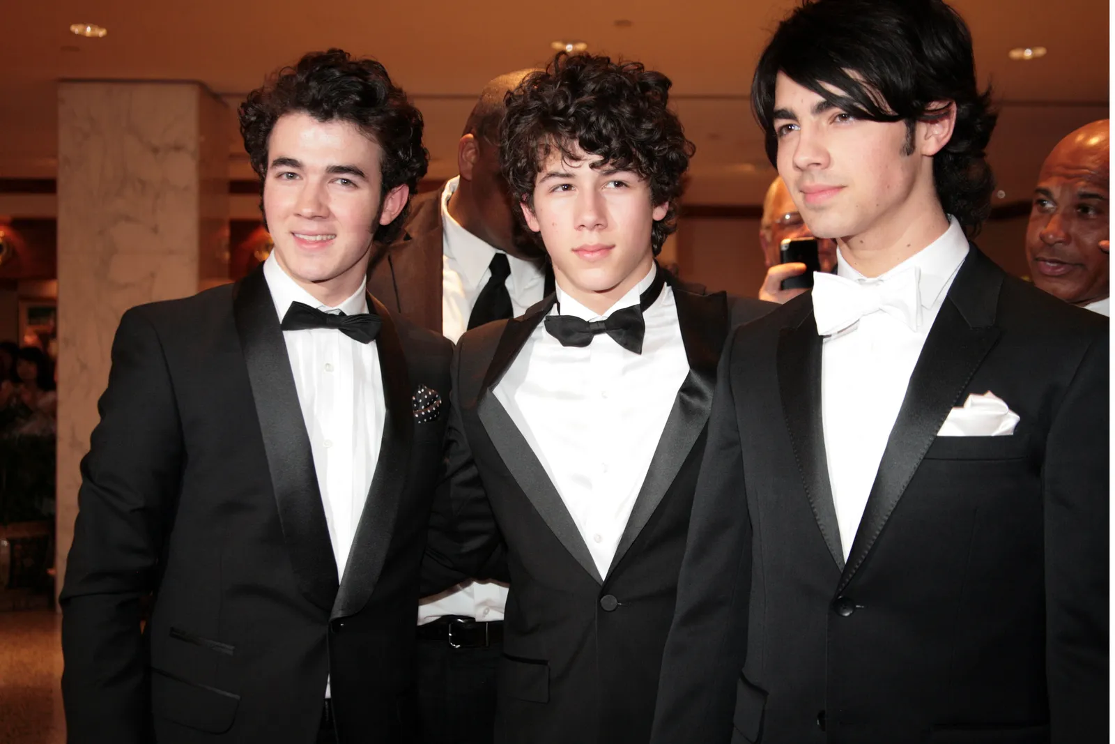 התמונה עשויה להכיל את ניק ג'ונאס קווין ג'ונאס ג'ו ג'ונאס ביגוד חליפת לבוש רשמי אביזרי טוקסידו עניבה ומבוגרים