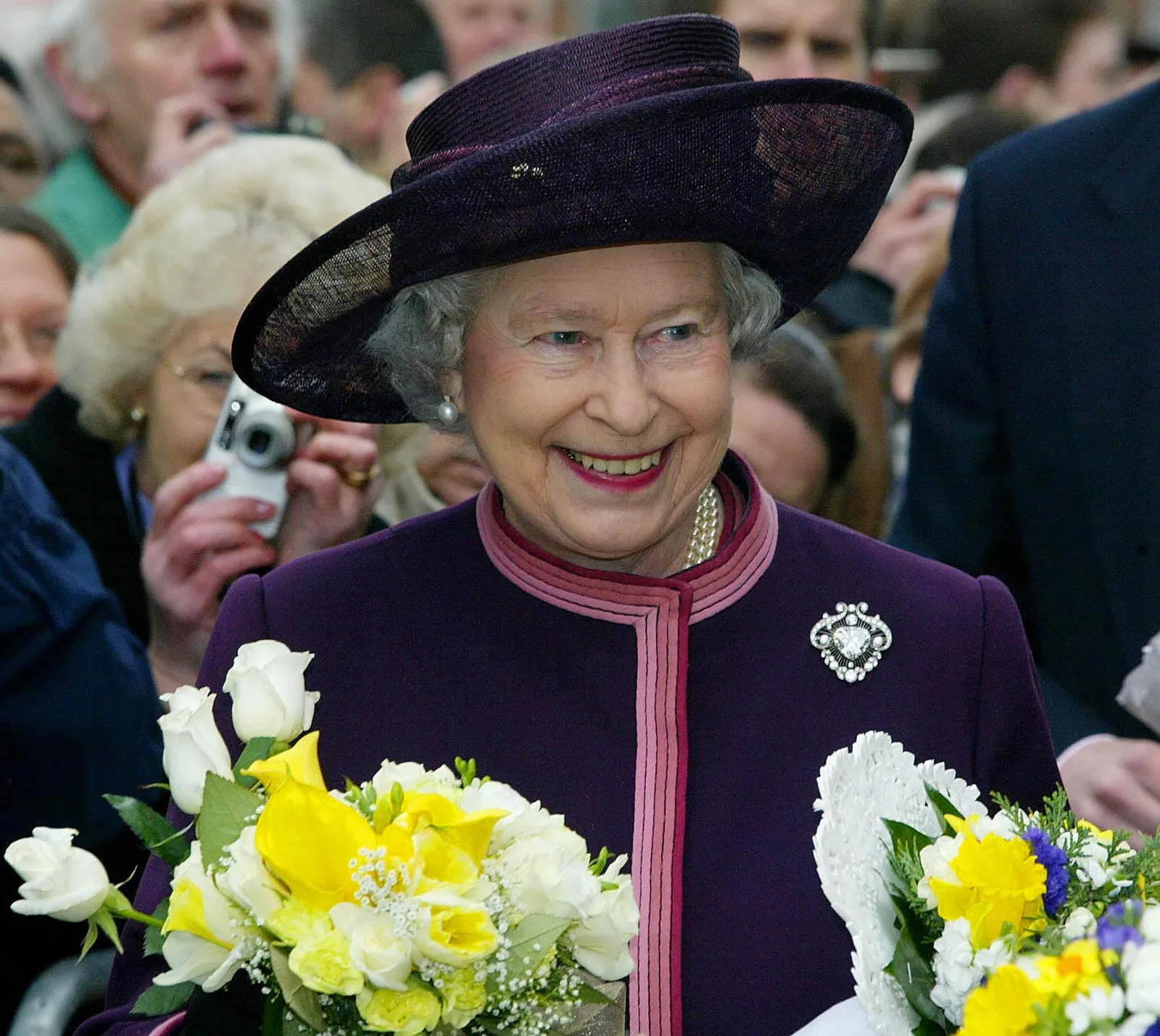 התמונה עשויה להכיל אליזבת השנייה אדם סידור פרחים צמח ביגוד כובע זר פרחים למבוגרים וחתונה