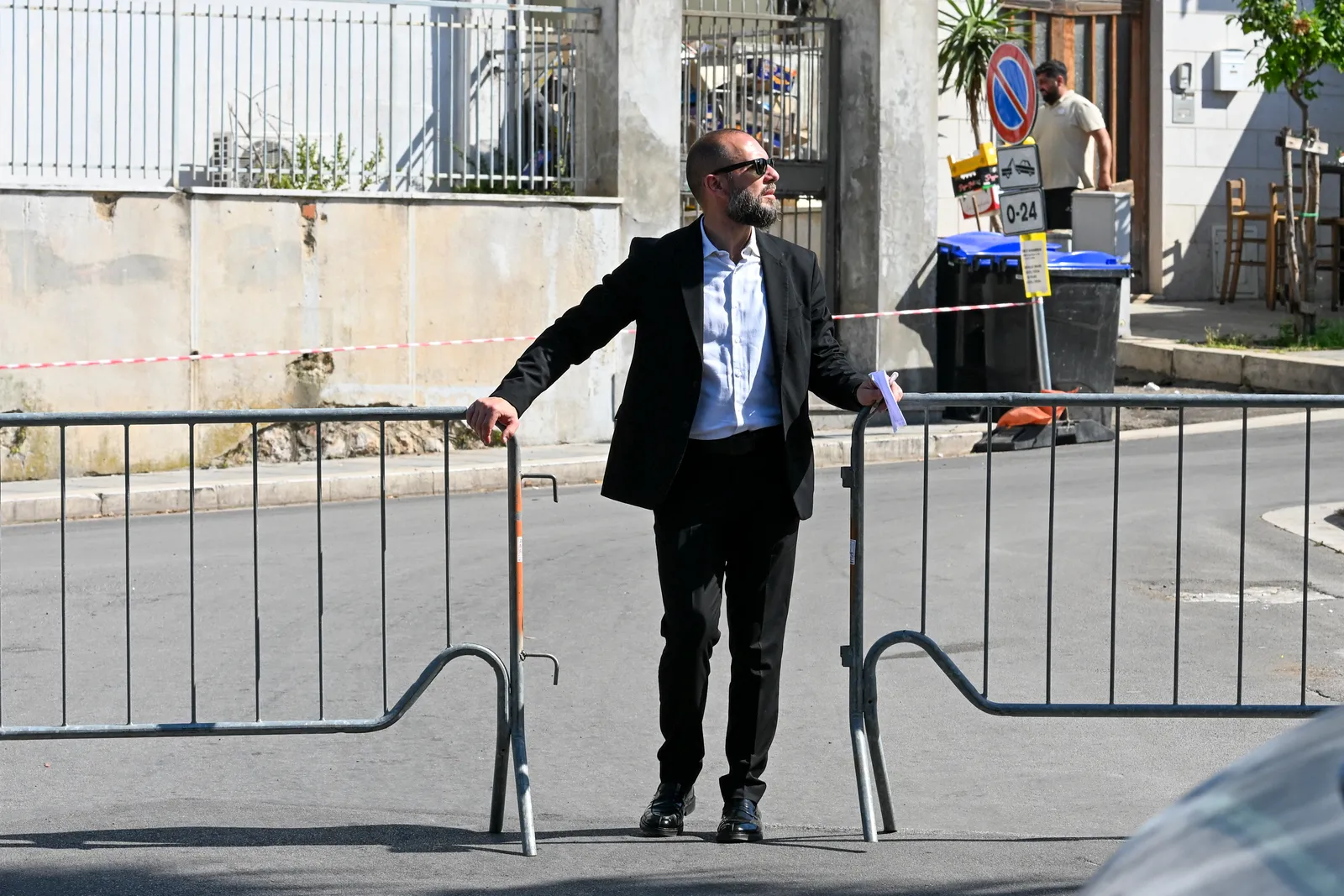 התמונה עשויה להכיל אדם הולך רגל ביגוד למבוגרים מעיל עומד חליפת לבוש רשמי הנעלה נעל ואביזרים